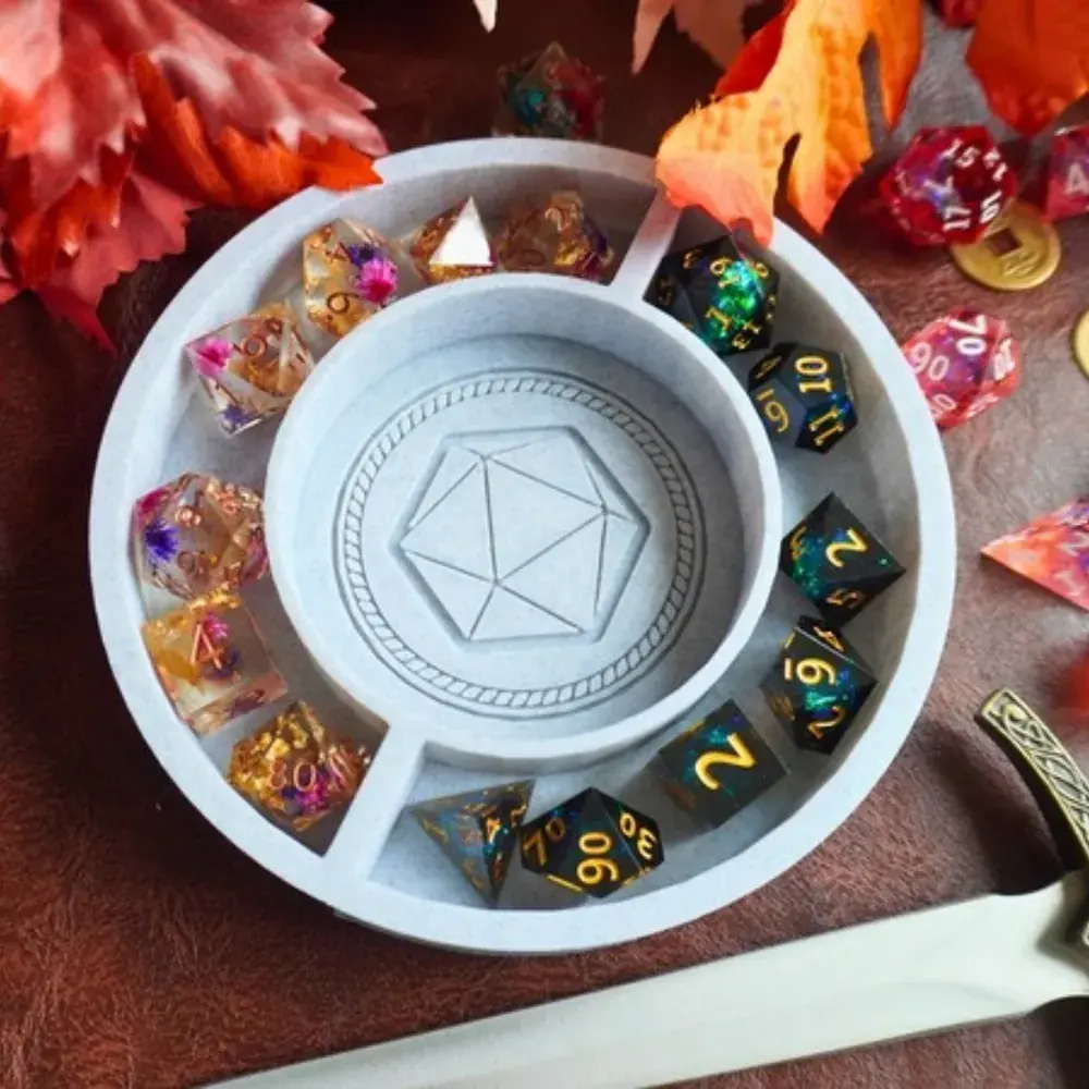 Grey marble D20 Round Dice Tray with two sets of resin dice in its rim compartments, on a leather mat with autumn leaves