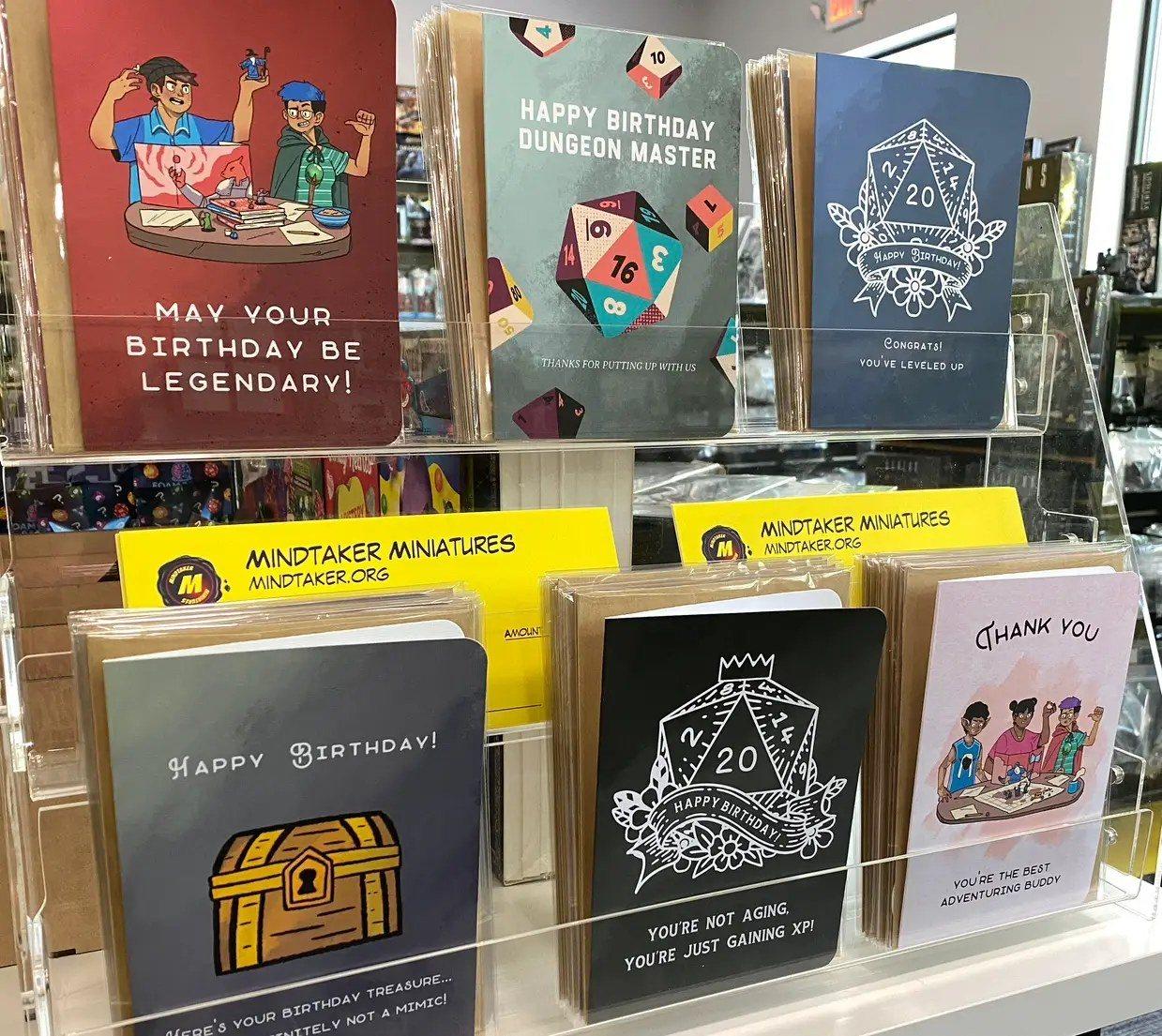 Minva greeting cards on a card rack at Mindtaker Miniatures